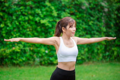 Woman with arms raised standing against plants