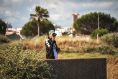 Man photographing while standing on field against sky