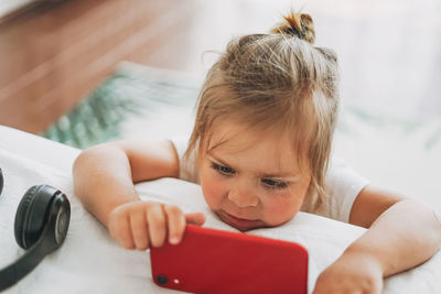 Close-up portrait of cute girl using laptop on bed at home