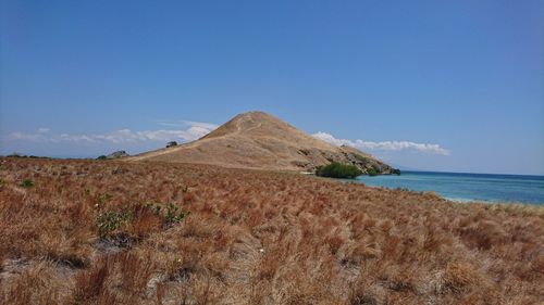 Scenic view of sea and hill against blue sky