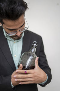 Midsection of young man holding bottle