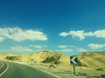 Road leading towards mountains against sky