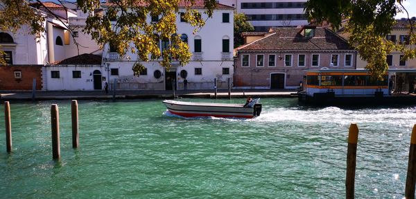 Boats moored in canal amidst buildings