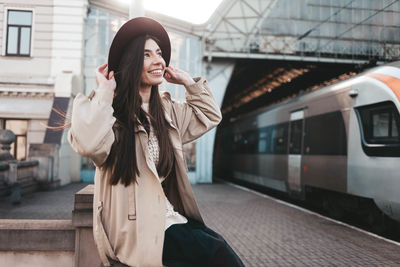Smiling girl in hat at train station waiting for train departure