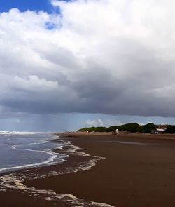 Scenic view of beach against cloudy sky