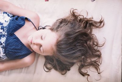 High angle view of girl with brown hair sleeping on bed at home