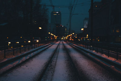 Snow covered railroad tracks in city at night