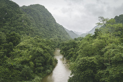 Scenic view of river amidst mountains against cloudy sky