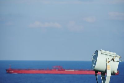 Close-up of coin-operated binoculars by sea against sky