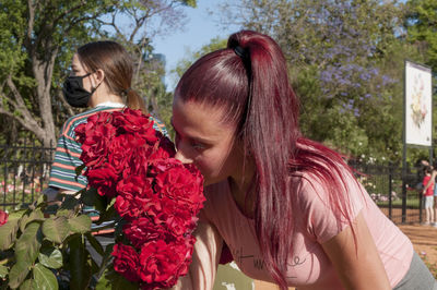 Rear view of women on red flowering plants