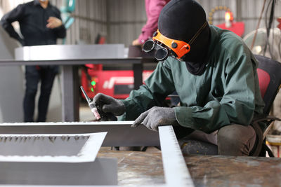 The worker is welding a steel frame in the workshop.