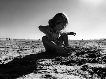 Girl on beach against clear sky