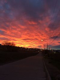 Silhouette road against dramatic sky during sunset