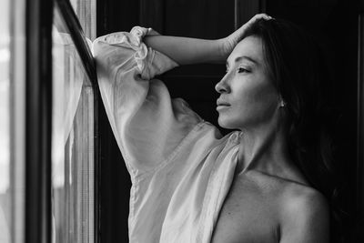 Side view of young woman looking through window