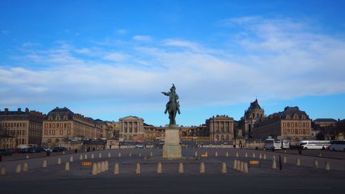 Statue in city against cloudy sky