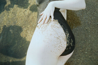 Midsection of sensuous woman in swimwear relaxing at sandy beach