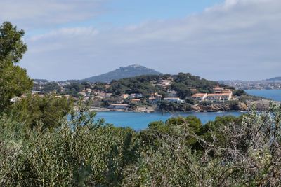 Scenic view of town by sea against sky