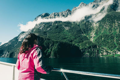 Rear view of woman standing by mountain against sky