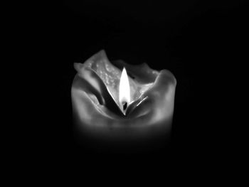 Close-up of lit candle in darkroom