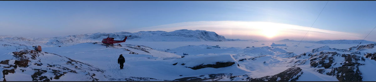 Rear view of man and helicopter on snowcapped mountains