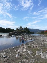 Man standing on rocks at beach against sky