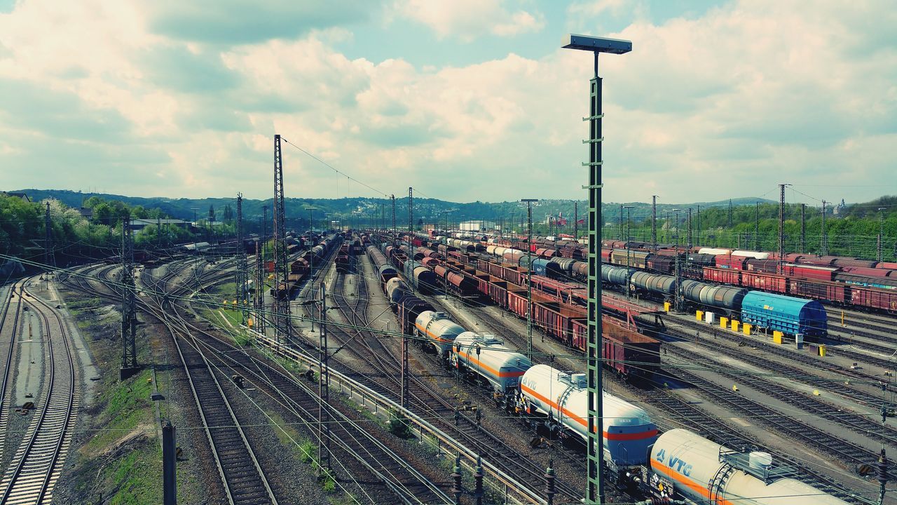 sky, cloud - sky, transportation, street light, cloudy, mode of transport, high angle view, city, panoramic, in a row, cloud, car, road, street, outdoors, built structure, day, land vehicle, building exterior, abundance