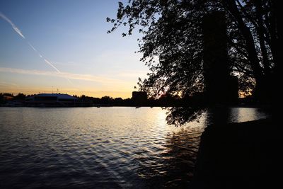 Silhouette trees by lake against sky during sunset