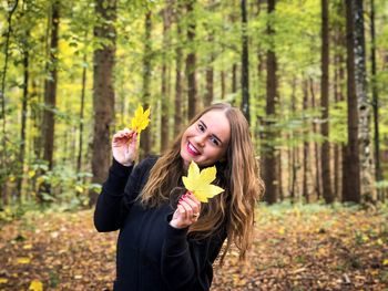 Beautiful young woman with autumn leaves in forest