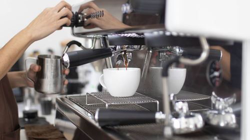 Cropped hand pouring coffee in cafe