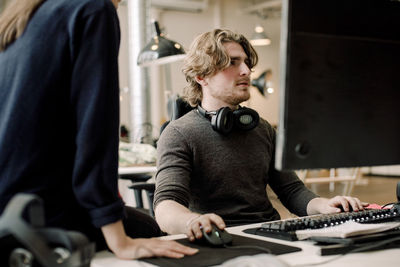 Midsection of entrepreneur with coworker sitting at workplace