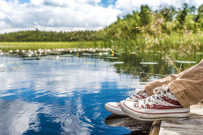 Low section of person sitting beside pond