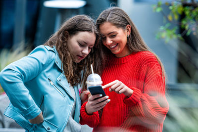 Portrait of a smiling young woman using mobile phone