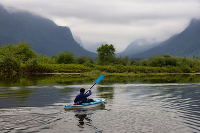 Man in boat on lake against mountains