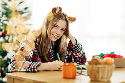 Portrait of a beautiful teenage girl writing a letter with congratulations 