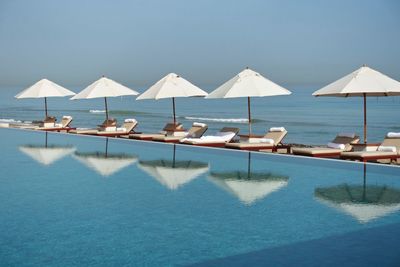 Sun loungers with canopies in row against calm blue sea