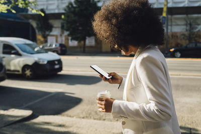 Businesswoman with coffee cup using mobile phone