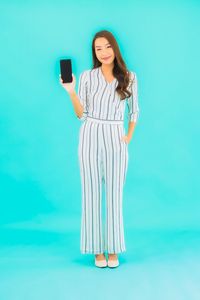 Young woman using smart phone against blue background