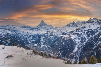 Majestic snow covered mountain range against cloudy sky during sunset in alps