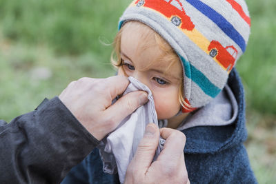 Close-up of person hand cleaning girl nose on land