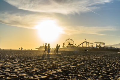 Silhouette people on beach at sunset