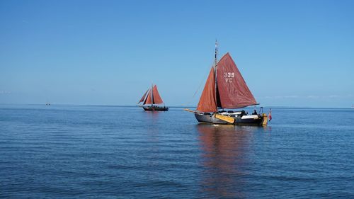 Sailboat sailing on sea against clear blue sky