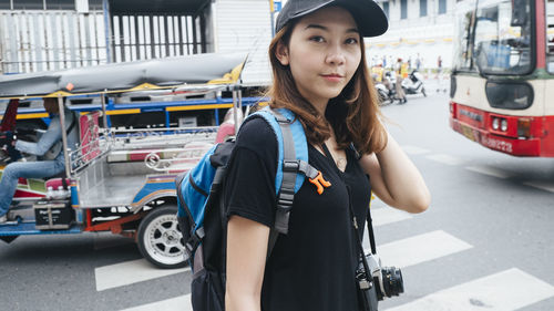 Portrait of young woman standing on street in city