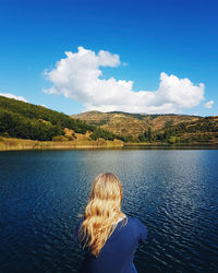 Rear view of person on lake against blue sky