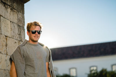 Young man wearing sunglasses standing against clear sky