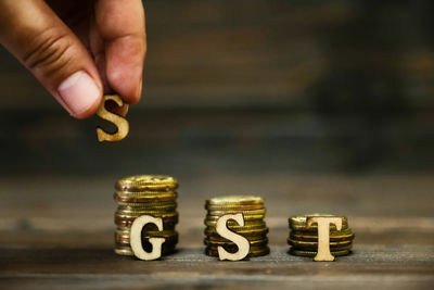 Cropped hand with gst text on stacked coins at table