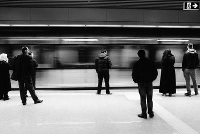 Rear view of people standing on railroad station platform against train