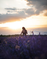 Rear view of person standing on field against sky during sunset