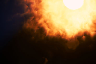 Defocused image of illuminated lights against sky at sunset