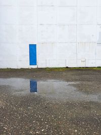 Blue door of factory reflecting in puddle