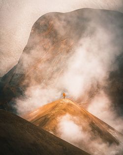 Person standing on mountain against sky